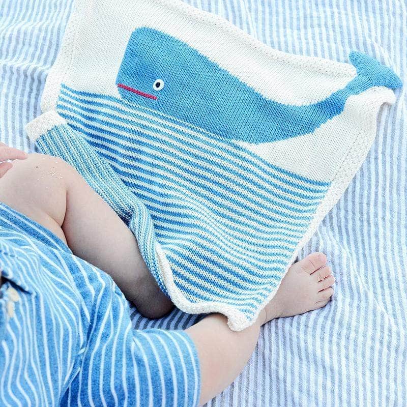 Organic cotton whale lovey blanket draped over a baby's feet — Estella