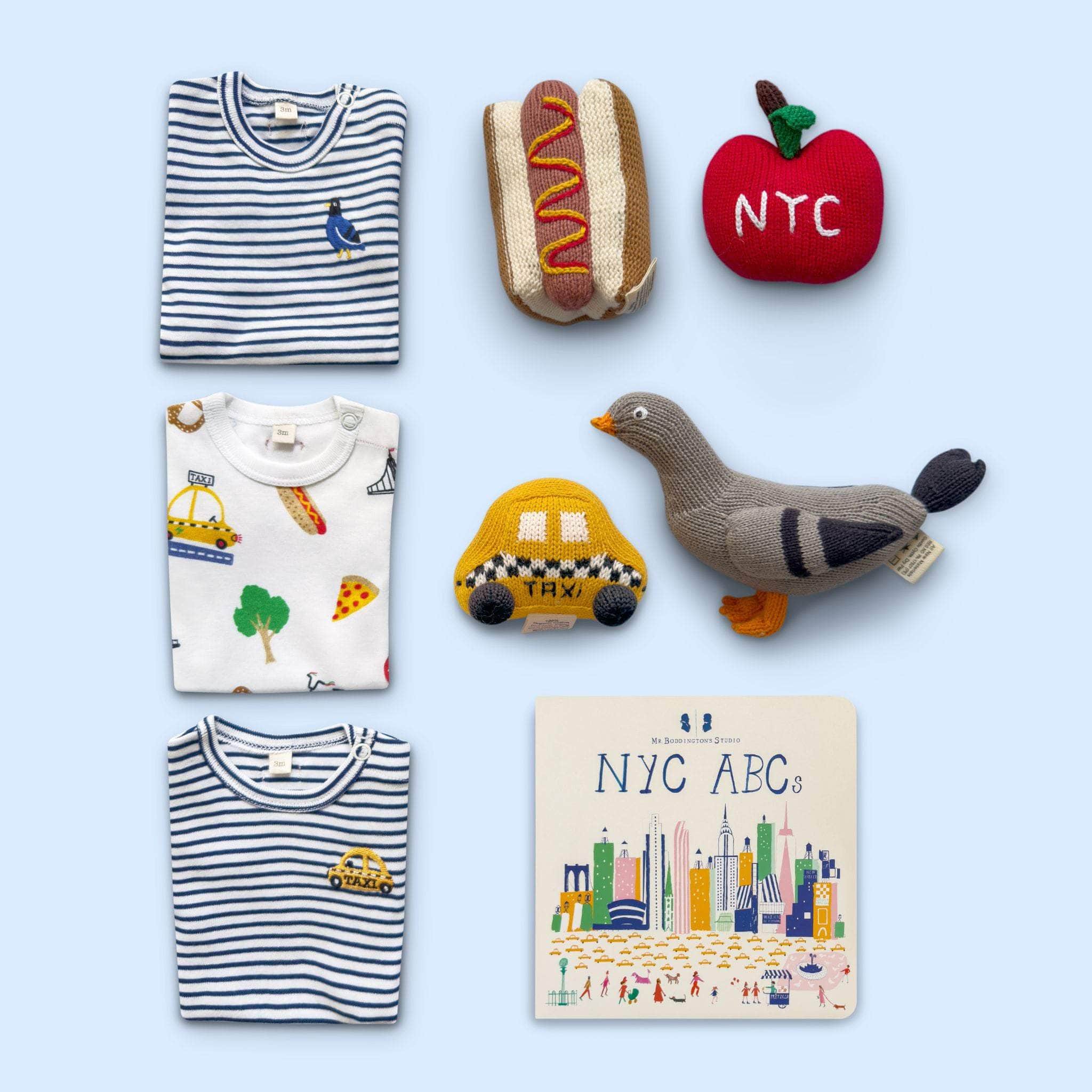 Estella Baby Gift Set with 3 Onepiece Bodysuits, 4 Rattle Toys & a Book on Blue Background.