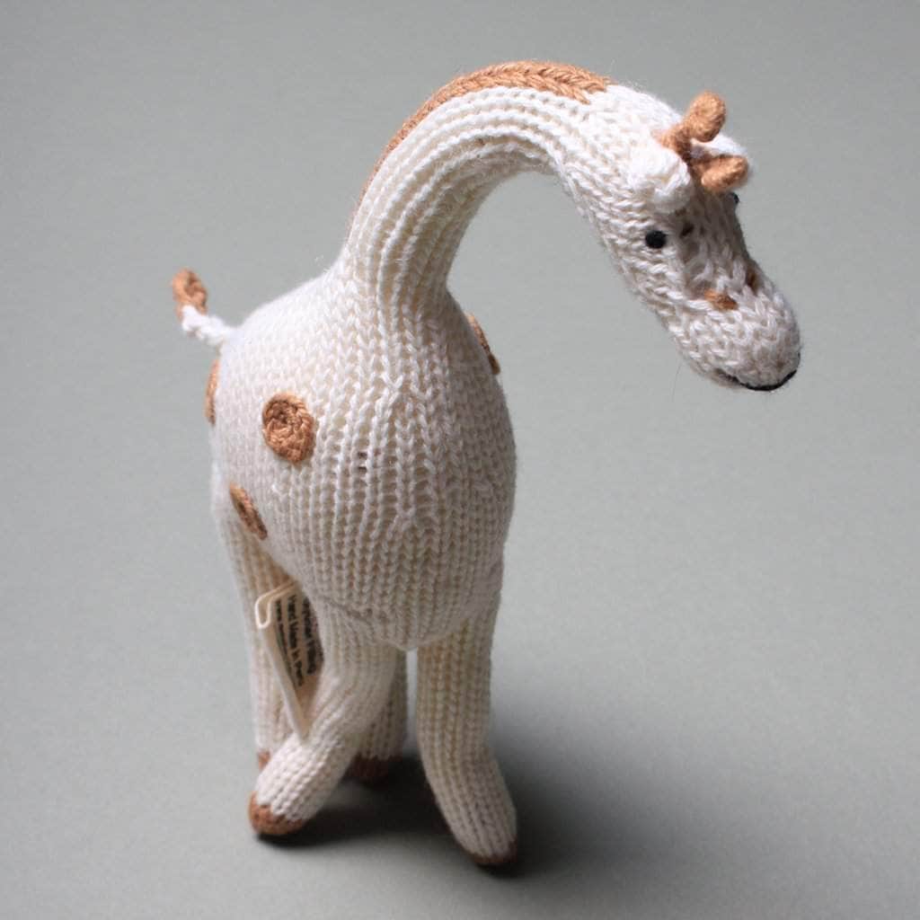 Cream-colored giraffe baby  rattle with soft brown spots. Giraffe teeters on a soft gray background.
