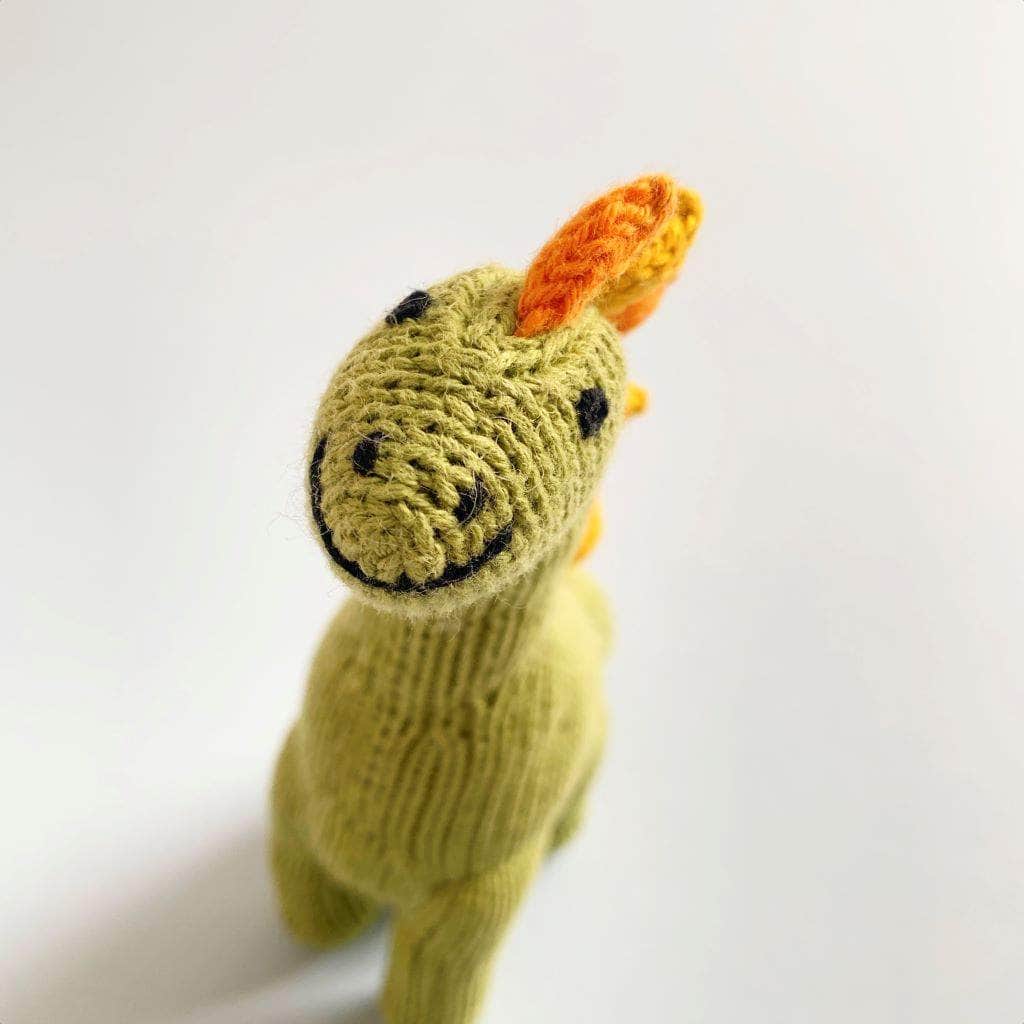 top view of baby rattle knit Brachiosaurus toy. Green, yellow, and orange.