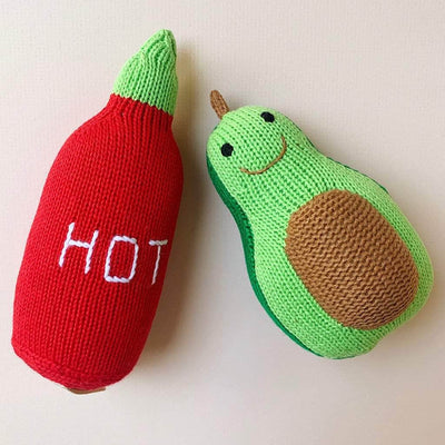 Organic baby toy rattles. Picture shows a red 'Hot" sauce shaped knit bottle with green top and a green avocado shaped toy with smiling face stitched on a lighter green half.
