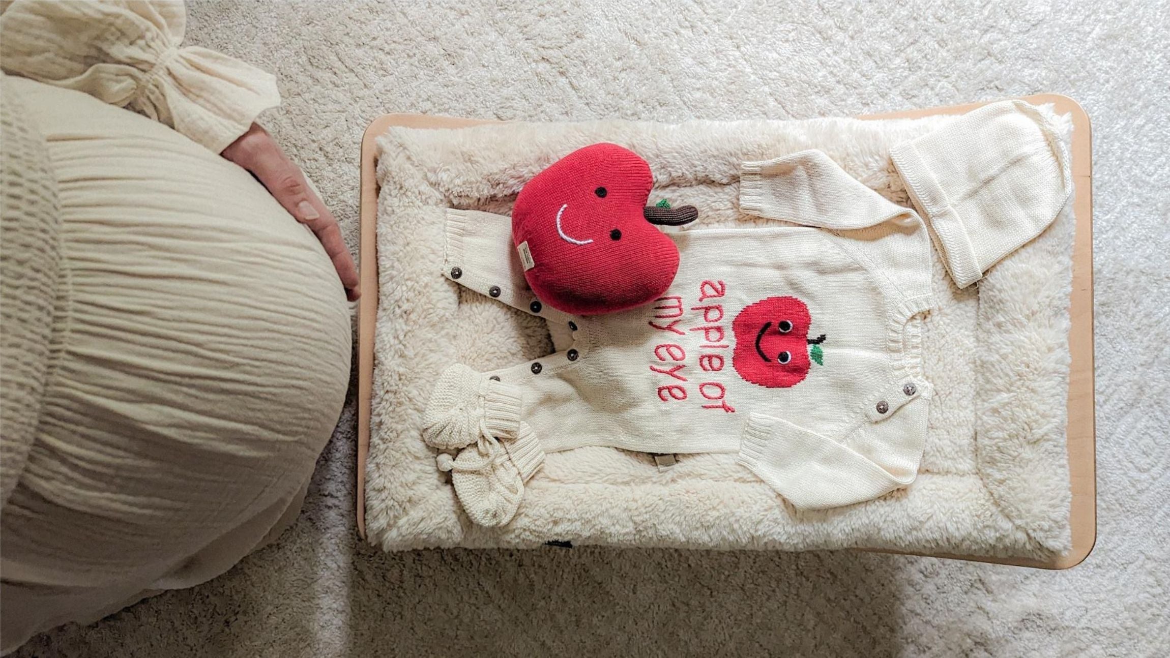 A pregnant mom looking at a baby gift set with an "Apple of My Eye" theme