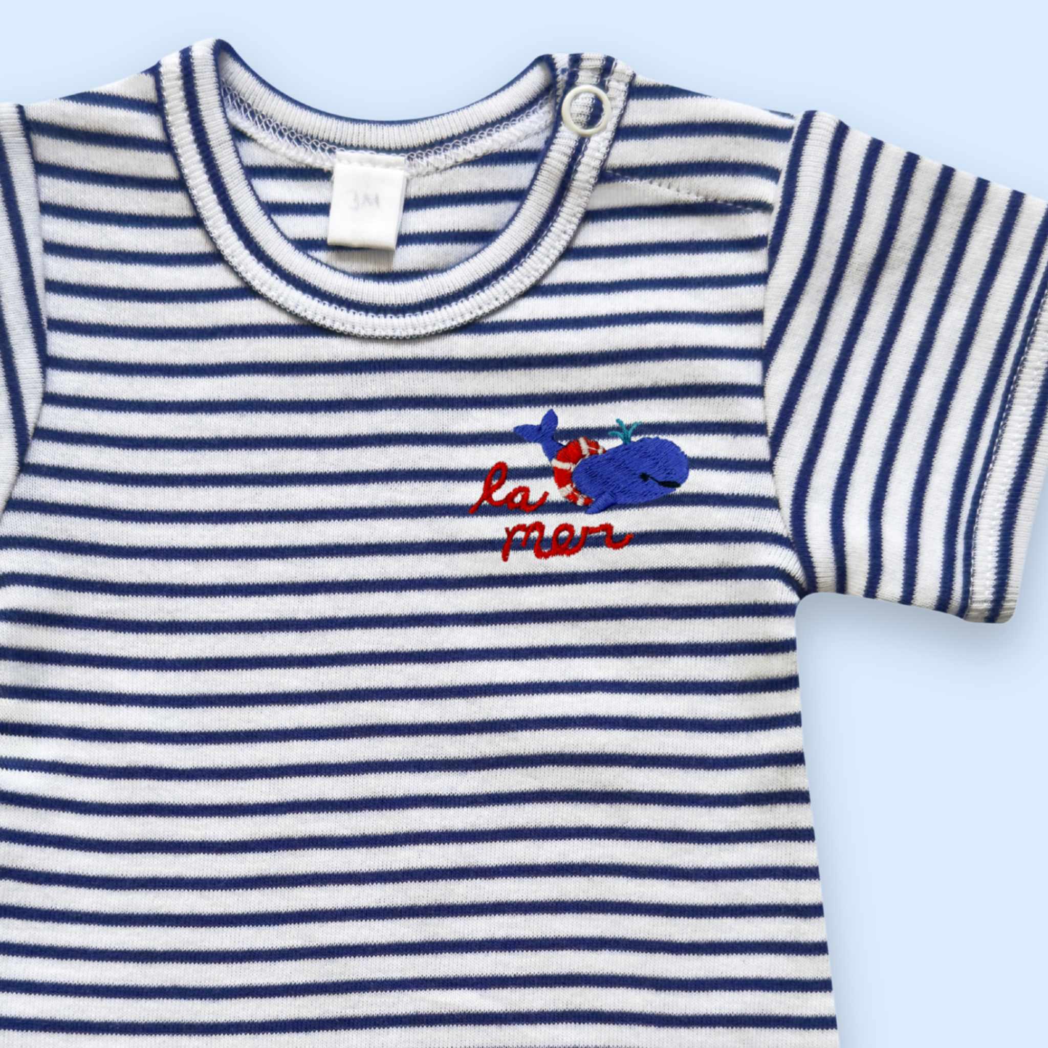 Estella Baby Clothes Organic La Mer Whale Embroidered Bodysuit. Detail showing the neckline with snap closure and embroidered whale.