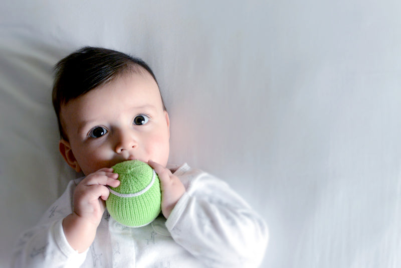 Baby holding a knitted tennis ball baby rattle