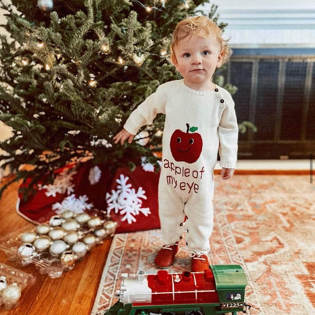 Toddler standing by Christmas Tree wearing Apple of My Eye romper