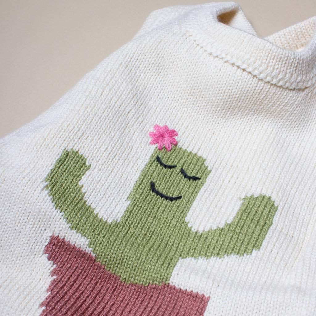 close up detail of sleeveless knit cactus romper. Cream, green, brown, pink. 