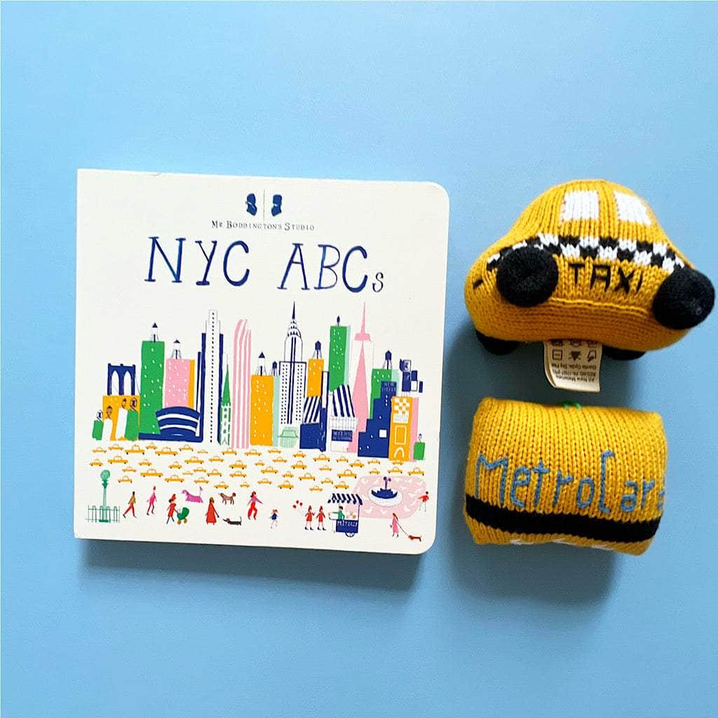 NYC ABCs baby board book with yellow knitted taxi and metrocard baby rattles.