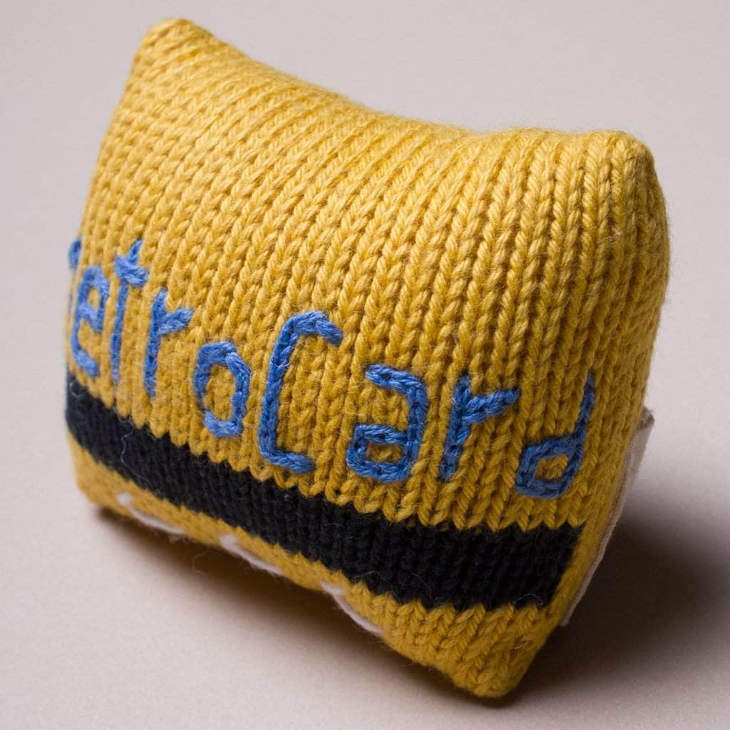 Yellow knitted baby metrocard rattle with blue embroidery.