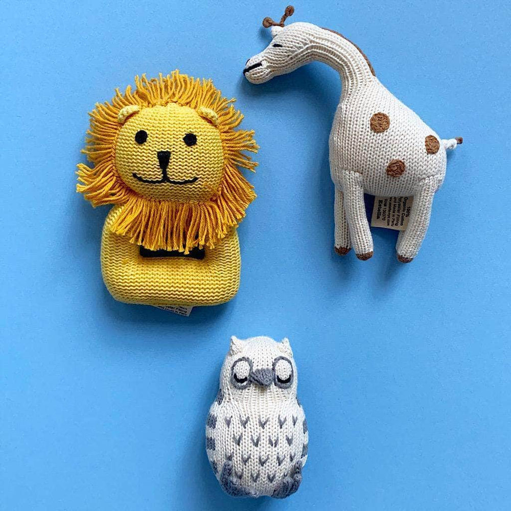 Photo of yellow lion rattle, cream and brown giraffe rattle and cream and gray owl rattle on blue background.