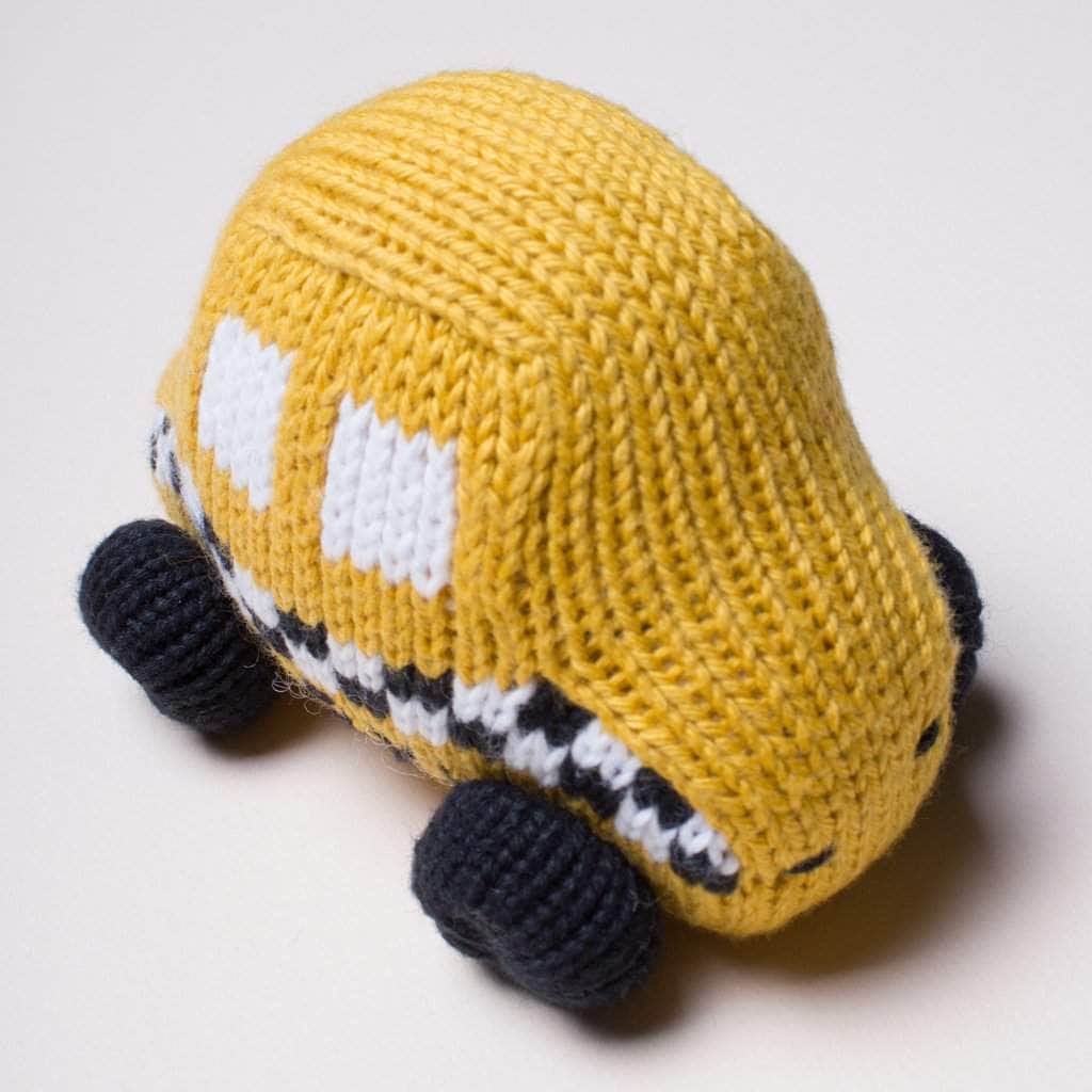 organic baby rattle taxi toy. Yellow, black and white checker and black wheels.