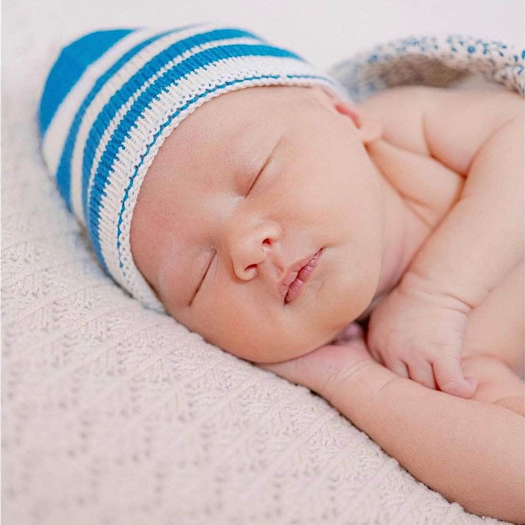 Sleeping infant wearing the organic cotton blue striped baby hat