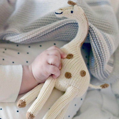 Soft Giraffe Baby Toy rattle in baby's hand showing that it is around 4 inches long.